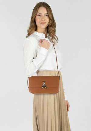 Bolso de hombro de cuero marrón con cierre de solapa y un adorno plateado en forma de insecto. Se lleva cruzado con una correa larga. Textura lisa.