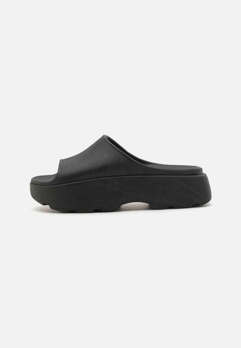 Sandales à enfiler noires avec une finition mate lisse. Dotées d'une semelle épaisse et rembourrée ainsi que d'un design minimaliste. Sans motifs ni accents visibles.