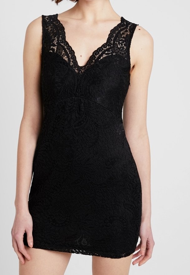 Robe mini noire en dentelle sans manches avec un décolleté en V et un motif floral délicat en dentelle sur une personne debout devant un fond uni.