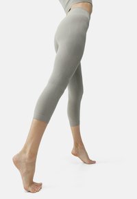 Šviesiai pilkos spalvos capri tipo leggingai, pagaminti iš lygaus, elastingo audinio, su aukštu liemeniu ir subtiliomis kreivomis siūlėmis.