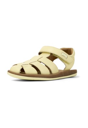 Keltainen nahkasandaali avoimella varpaalla ja sivuleikkauksilla. Varustettu tarranauhalla ja ruskealla pehmustetulla pohjallisella. Kevyt muotoilu.