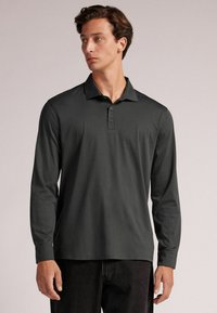 Langsleeve polo shirt in donkergrijs, gemaakt van zachte stof, met een drieknoopsluiting en een klassieke kraag. Gladde textuur, getailleerd design.