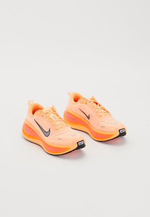 Une paire de chaussures de course Nike ZoomX orange vif avec des logos swoosh noirs et des semelles épaisses et rembourrées sur un fond blanc.