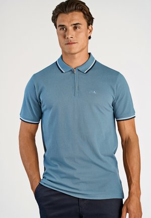 Kortærmet polo-shirt i lyseblå, med en lynlås krave og kontrasterende navy og hvide striber på kraven og ærmerne.