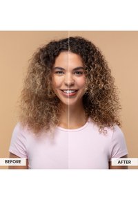 Kręcone włosy pokazane w dwóch stanach: lewa strona puszysta z jasnobrązowymi i blond pasemkami; prawa strona zdefiniowane loki, gładsza tekstura. Tło jest beżowe.