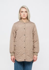 Beige quiltots jaka ar apaļu kaklu, pogu aizdari un ribotām piedurkn�ēm. Audumam ir viļņaina tekstūra un brīvas piegriezuma siluets.