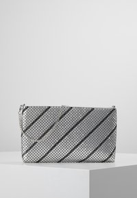 Stříbrná obdélníková kabelka na večer s řetízkovým popruhem, která má síťovou texturu a diagonální černé pruhy. Kompaktní design s hladkým povrchem.
