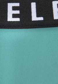 Svetlomodrá rebrovaná látka s čiernym pásom, na ktorom je biele písmo. Textúra je hladká a dizajn je minimalistický.