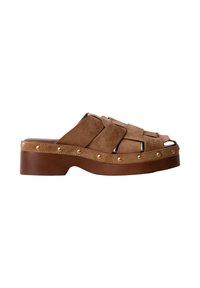 Sandale plateforme en daim marron avec des brides croisées et des clous dorés le long du bord de la semelle sur un talon bloc.