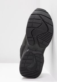 Semelle de basket noire avec des motifs de bande de roulement variés, incluant des motifs en grille et en ligne, sur une surface blanche avec un fond blanc.