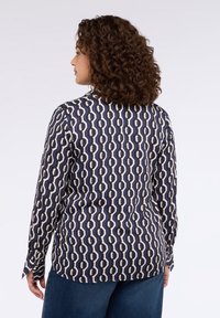 Granatowa koszula z geometrycznym wzorem w kolorach kremowym i beżowym, długie rękawy, kołnierzyk oraz mankiety zapinane na guziki, o dopasowanym kroju i gładkiej fakturze.