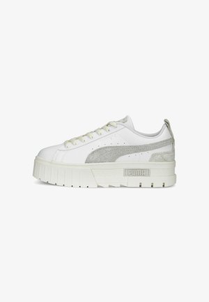 Baltas sneakers ar tekstūrētu pelēku zamša svītru, biezs balts zole un plakani šņores. Tiem ir apaļš purngals un mīksts apkakle komfortam.