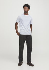 Light blue cotton t-shirt with short sleeves and a round neckline, paired with dark grey straight-leg jeans and brown lace-up shoes.