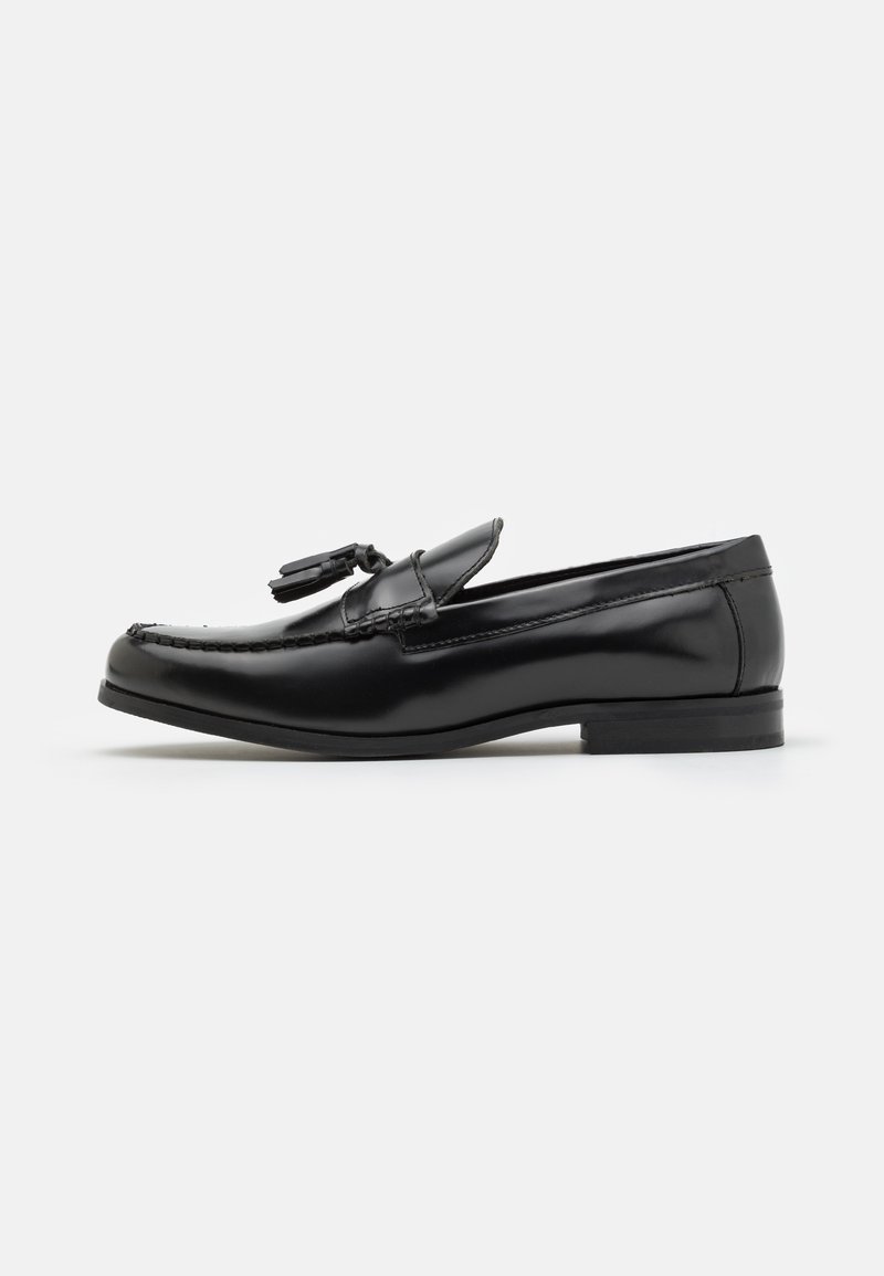 Mustad mustad nahast loafers sileda viimistlusega, puhevate aksessuaaride ja õmmeldud kujundiga varvaste juures. Kergelt kõrge kand ja ümar kuju.