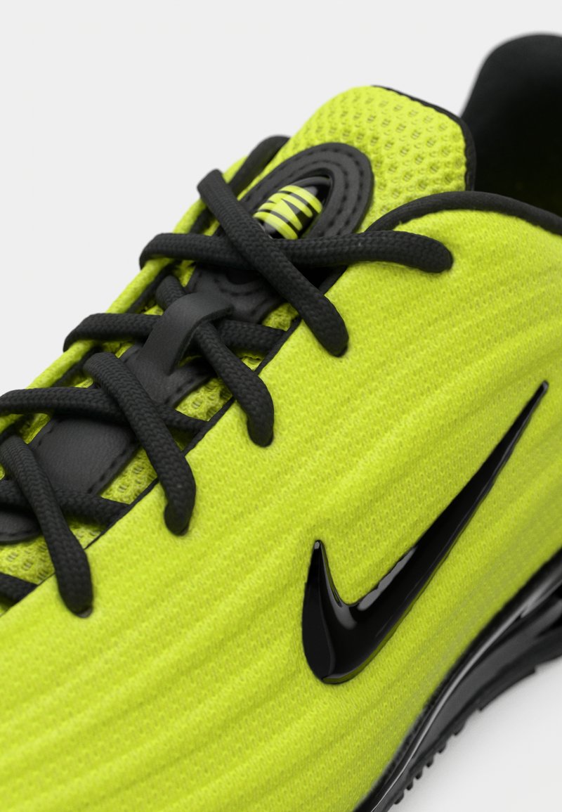 Lysande grön sportskor med svarta snörningar, luftkuddesula och en skinande svart Nike swoosh-logo på sidan.