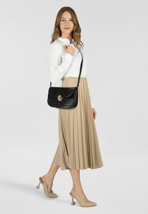 Bolso bandolera de cuero negro con textura de cocodrilo, herrajes dorados y cierre con solapa. Combinado con una blusa blanca y una falda plisada beige.