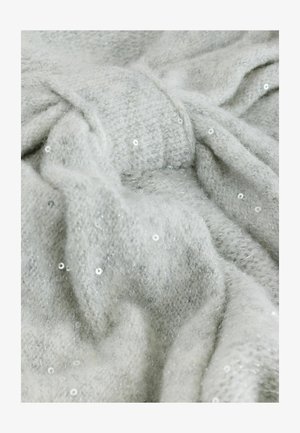 Világosszürke kötött anyag, finom, puha textúrával, amelyen apró, fénylő paillettok szóródtak szét. Az anyag kellemes és réteges megjelenésű.