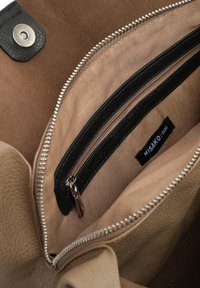 Wnętrze brązowej torebki z zamszu z beżowym wykończeniem, czarną kieszonką na zamek błyskawiczny oraz srebrnym detalem zamka. Widać metkę "MISAKO".