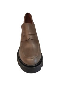 Zapato slip-on de cuero marrón claro con punta cuadrada, detalles de costura y una suela de goma negra gruesa. Textura suave con acentos mínimos.