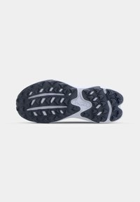 Svart og hvit idrettssko såle med dype spor og fremtredende grep-lugger, laget av gummi med en teksturert overflate. HOKA-merke synlig.