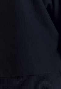 Navy blue sweatshirt fabric with a textured surface, featuring a ribbed hem and cuffs. Seam detail visible, medium-weight material.