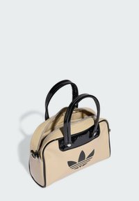 Beige patent leather handbag with black accents and handles, featuring a prominent black logo on the front. Zippered main compartment.