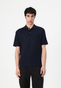 Polo shirt bleu marine à manches courtes en tissu doux avec un col, doté d'une patte de boutonnage à trois boutons et d'une coupe décontractée. Sans motifs ni accents.