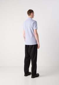 Hellblaues Poloshirt mit kontrastierendem weißen Besatz, kurzen Ärmeln und schmaler Passform. Tragen Sie dazu schwarze weit geschnittene Hosen und schwarze Schuhe.