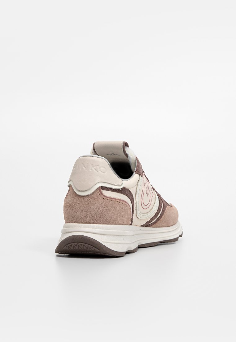 Sneaker in suede beige e marrone con suola bianca vista da dietro, che mostra il nome del marchio impresso sulla linguetta del tallone.