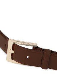 Ruskea nahkavyö, jossa on kultasävytteinen suorakulmainen solki, jossa on kaiverrettu brändinimi, sekä useita reikiä säädettävyyttä varten.