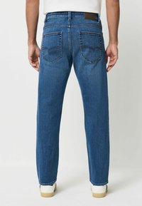 Siniset farkut suoralla lahkeella, joissa on kaksi takataskua, hienovaraiset ompeluyksityiskohdat ja sileä pinta.