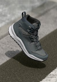 Donkergrijze mid-length wandelschoenen met een gestructureerde bovenkant, vetersysteem en een witte zool. Voorzien van GORE-TEX merklogo en een gevoerde kraag.