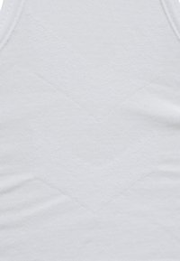 Witte stof in close-up met subtiele geperste chevronpatronen en fijne gestructureerde stikdetails.