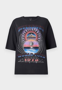Black oversized t-shirt featuring a colorful graphic design with mountains, sun, and water elements. Text includes "Billabong World Tour 1973."
