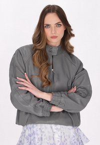 Jachetă bomber din piele gri, cu guler înalt, închidere cu fermoar și manșete elastice; are o suprafață texturată și două buzunare frontale.