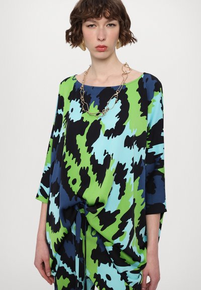 Loose-fitting, bold-patterned top in green, blue, and black; features a rounded neckline and three-quarter sleeves with a knotted detail at the hem.