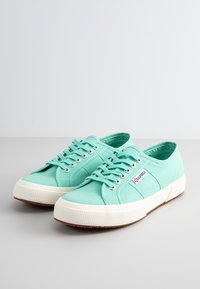 Miętowe kanwy trampki z metalowymi oczkami, płaskimi sznurowadłami, białymi gumowymi podeszwami i teksturowanymi detalami. Naszywka z logo po boku.