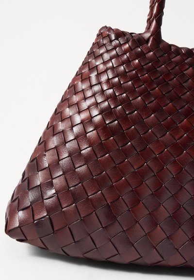 Υφασμένη δερμάτινη τσάντα σε σκούρο μπορντό. Διαθέτει τριγωνικό σχήμα με υφή στην επιφάνεια, αναδεικνύοντας ένα περίπλοκο σχέδιο και μια ανθεκτική λαβή.