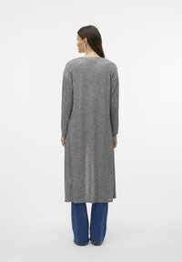Grå långärmad klänning med avslappnad passform, med rund halsringning och ankellång fåll, kombinerad med blå vida jeans.