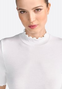 Hvid ribbet turtleneck-top med en bølget krave og korte ærmer, med glat tekstur og tætsiddende design.