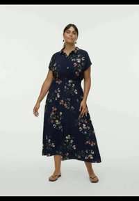 Vestido floral azul-marinho com mangas curtas, frente abotoada e saia fluida, apresentando padrões florais coloridos sobre um fundo escuro.