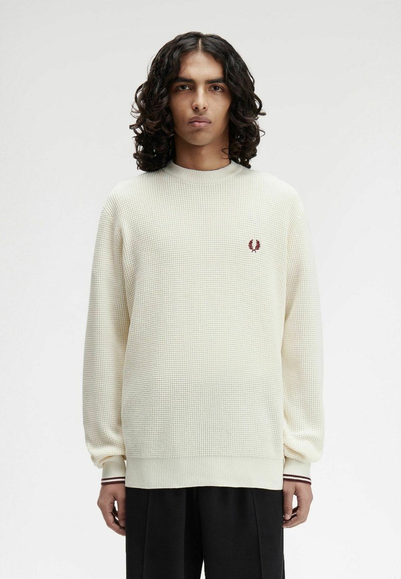 Cremfarbener, strukturierter Strickpullover mit rundem Hals und gerippten Bündchen. Mit einem kleinen burgunderfarbenen Logo auf der linken Brust.