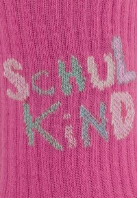 Różowe, dziane skarpetki z napisem "Schul Kind" w różnych pastelowych kolorach, o fakturowanej tkaninie i lekko prążkowanym designie.