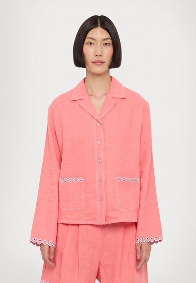 Veste en lin corail à boutons, avec manches longues, présentant des accents brodés blancs, deux poches avant et un design décontracté.