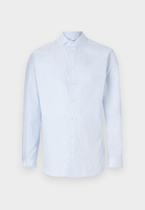 Chemise bleu clair à manches longues, à boutons, fabriquée en tissu lisse. Elle présente un col classique et cinq boutons à l'avant avec un ourlet arrondi.