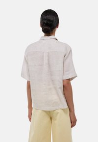 Chemise à manches courtes, rayée beige clair, à coupe ample avec un empiècement au dos. Tissu texturé avec un éclat subtil, associée à un pantalon jaune clair.