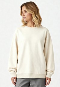 Sweatshirt color crema con scollo a girocollo, spalle scese e polsini e orlo a coste. Morbido al tatto, vestibilità rilassata, design minimal.