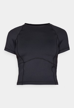 Sort atletisk crop top med korte ærmer og synlige sømme på ensartet lys baggrund.