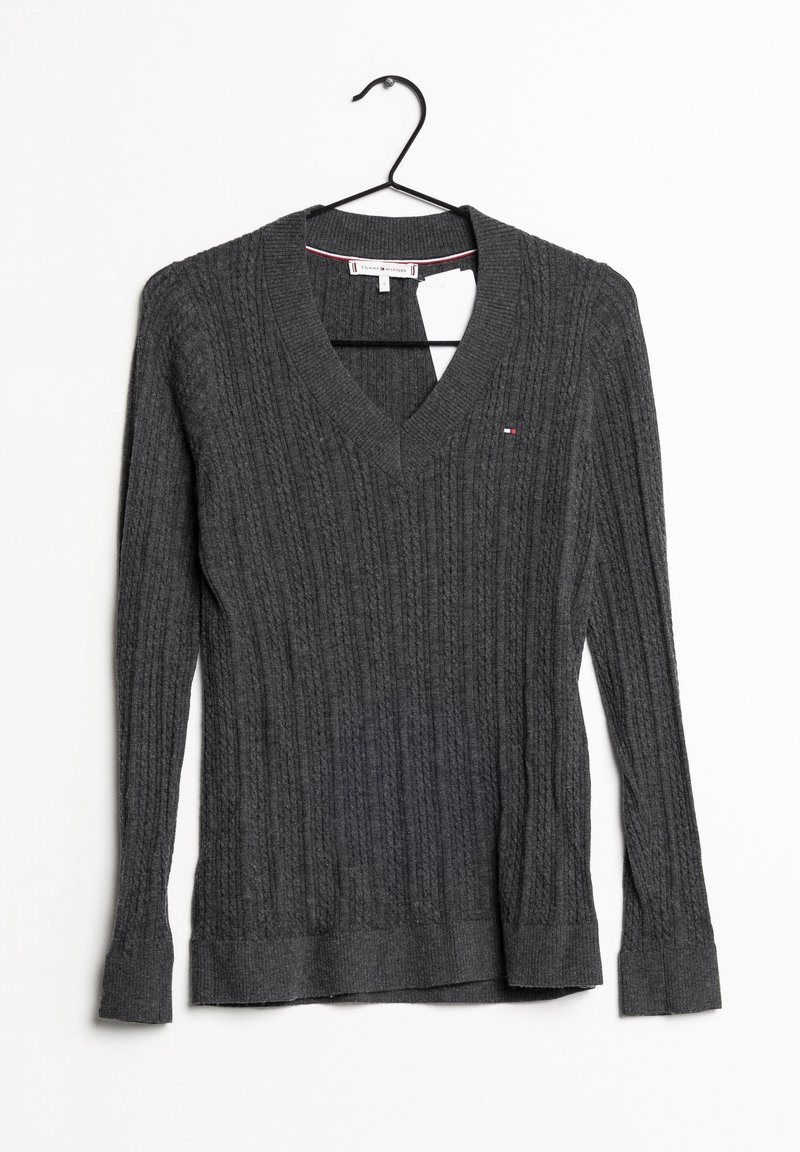Grijze gebreide trui met een V-hals en ribbeltextuur. Heeft lange mouwen en een klein logo op de borst. Hangend aan een zwarte haak.