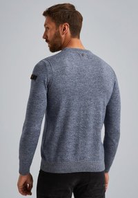 Maglione a maglia blu melange con maniche lunghe, polsini e orlo a coste, caratterizzato da un piccolo logo sulla spalla sinistra e un dettaglio con bottoni sul retro.